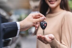 A man hands a car key to a woman, symbolizing a successful towing service assistance