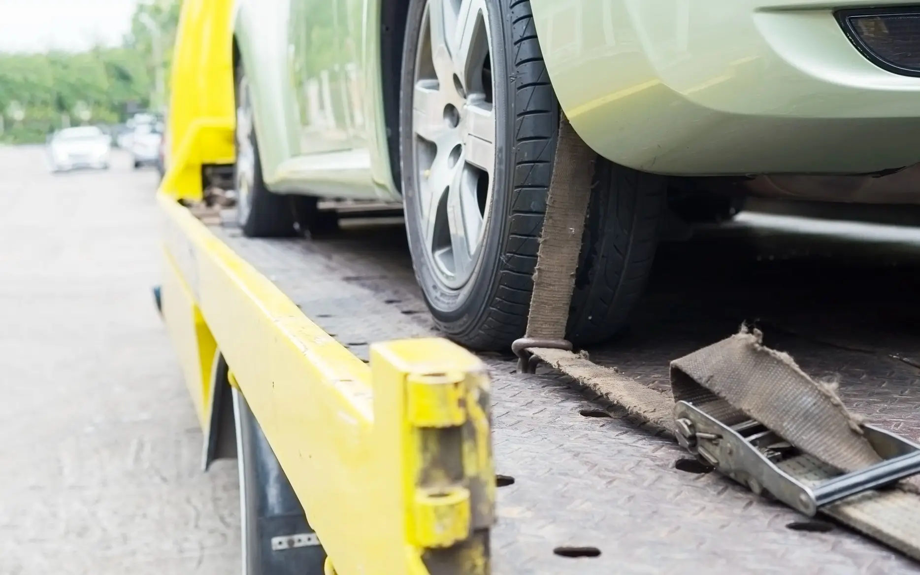 A yellow car being towed by a flatbed truck, demonstrating a reliable 24 hour towing company in action.